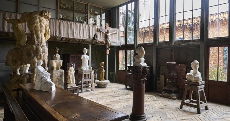 Un sculpteur travaillant méticuleusement sur une sculpture bois visage, montrant le grain du bois et les outils de taille